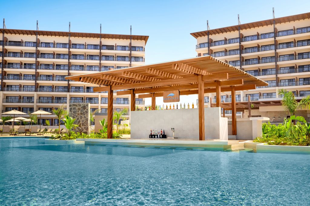 Bar area by the pool at Dreams Estrella del Mar Mazatlán Golf & Spa Resort, surrounded by lush greenery and modern architecture.