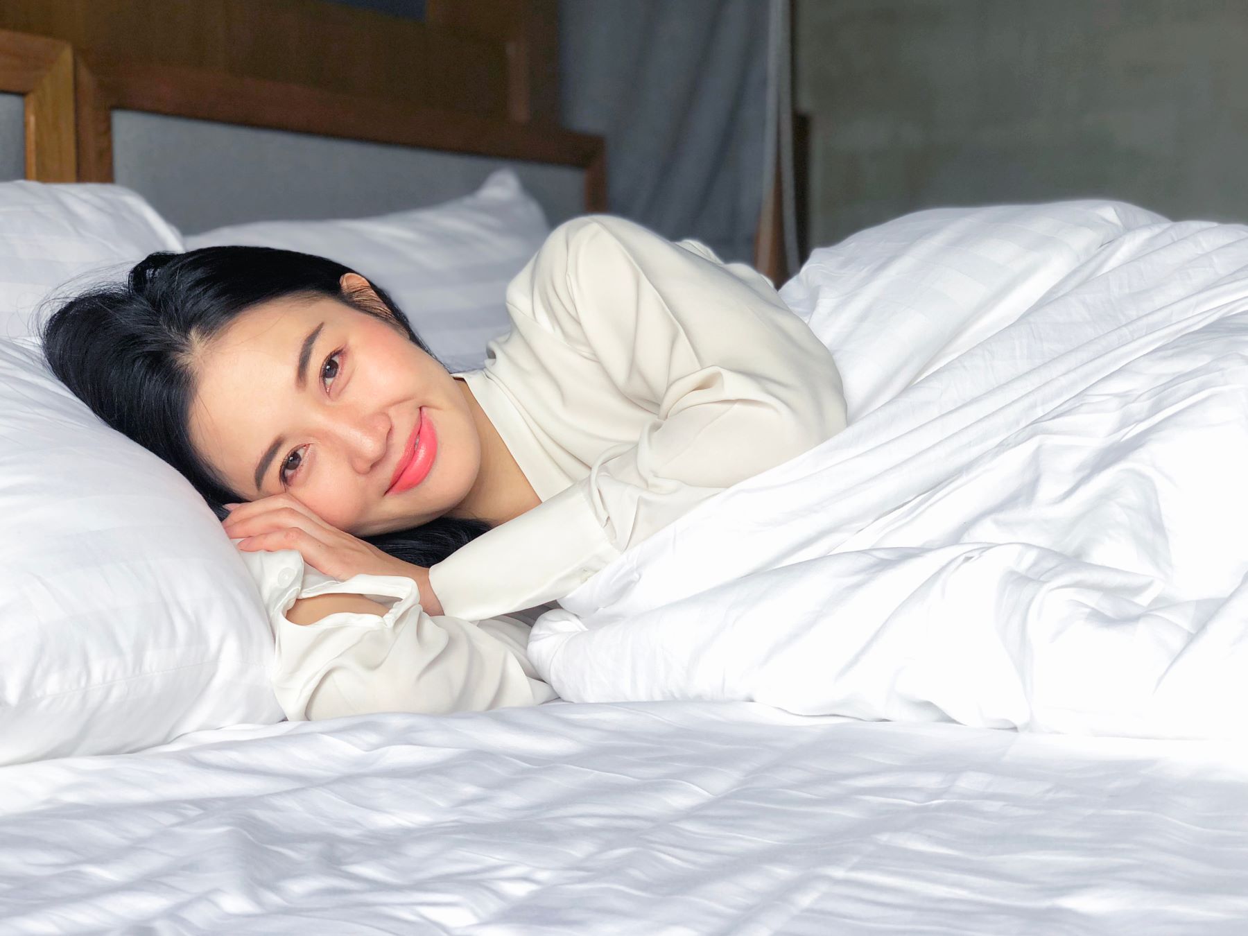 Woman resting comfortably on a bed with white sheets, illustrating the comfort of using absorbent pads.