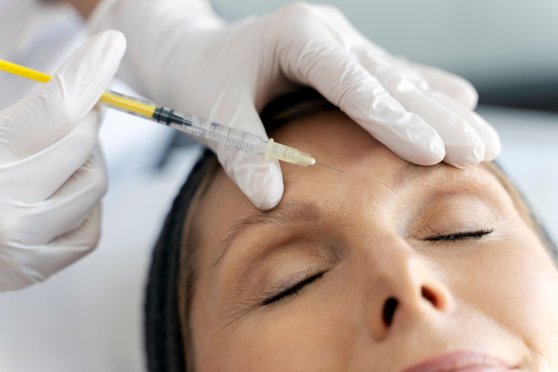 A healthcare professional administers a Dysport injection to a woman's forehead.