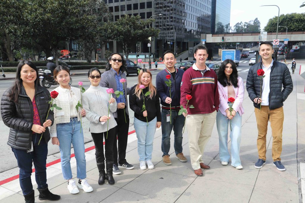 Group of people holding roses together in a city setting, promoting love and dining for Valentine's Day in LA.