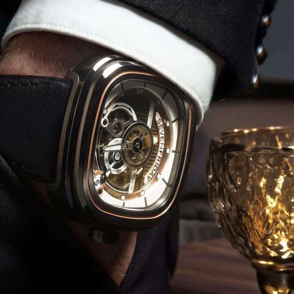 SEVENFRIDAY PS2/03 "BC" watch displayed on a wrist, featuring a skeleton design and elegant details with a glass tumbler nearby.