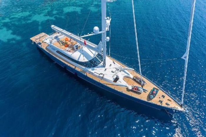 Luxury gulet yacht anchored in clear blue waters, showcasing the top deck and sails.