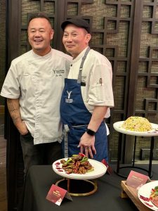 Chefs Jet Tila and another chef pose with a platter featuring a vibrant dish at Yaamava's Lunar New Year celebration.