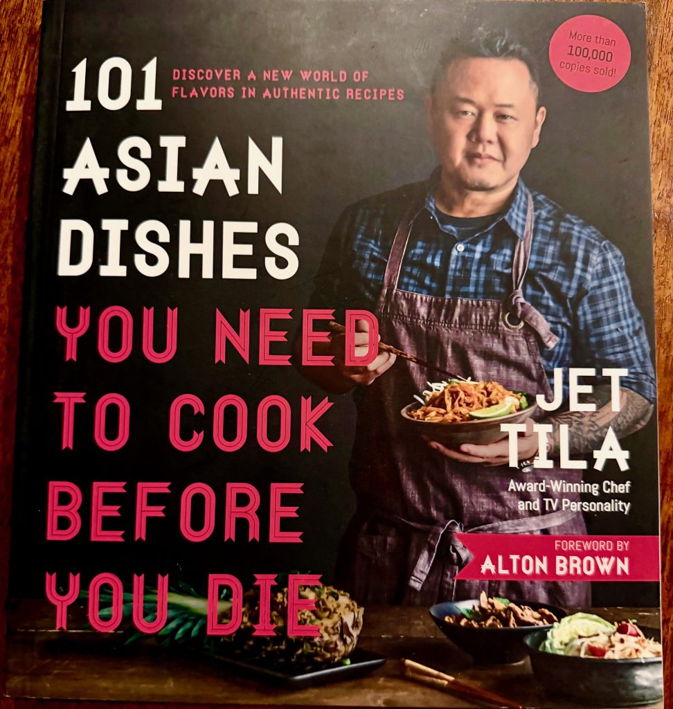 Jet Tila holding a plate of Asian dishes from his cookbook "101 Asian Dishes You Need to Cook Before You Die."