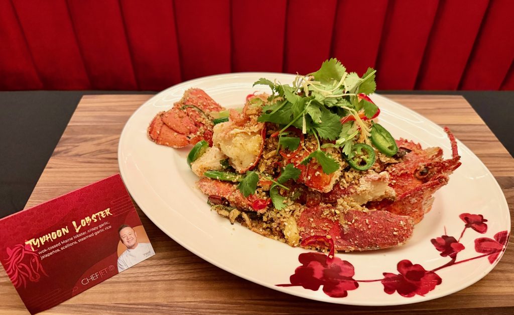 Wok-tossed Maine lobster dish with crispy garlic, jalapeños, scallions, and cilantro, presented at a Lunar New Year celebration.