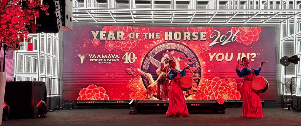 Dancers perform on stage at Yaamava's Lunar New Year celebration, with vibrant decorations and a "Year of the Horse" backdrop.