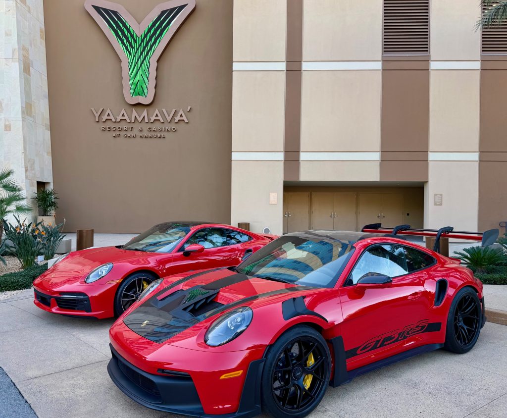 Two red sports cars parked in front of the Yaamava' Resort and Casino, showcasing modern design and sleek lines.