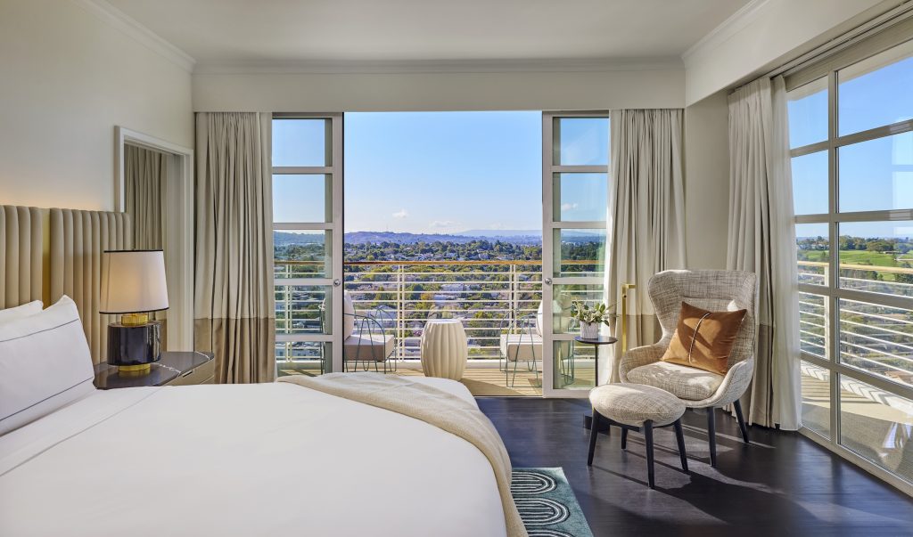 Luxury bedroom suite at Cameo Beverly Hills, featuring a view of the city and outdoor seating area.