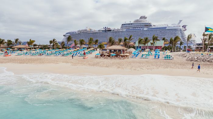 Royal Caribbean's all-inclusive Royal Beach Club at Paradise Island, featuring lounge chairs and a cruise ship in the background.