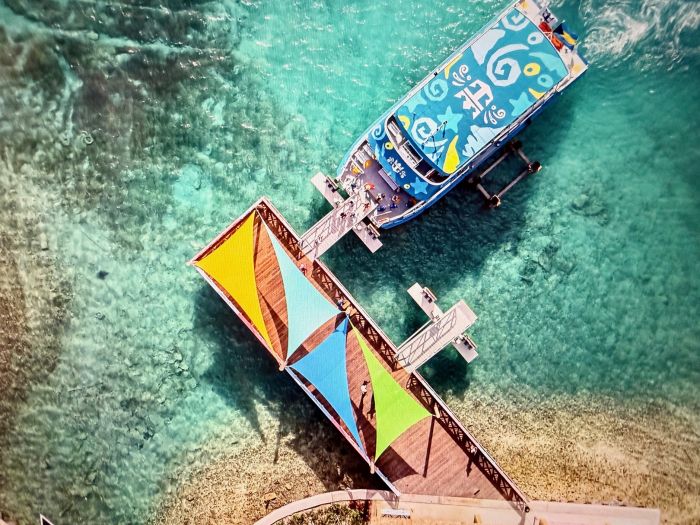 Aerial view of a colorful beach club dock with a boat moored in turquoise waters.