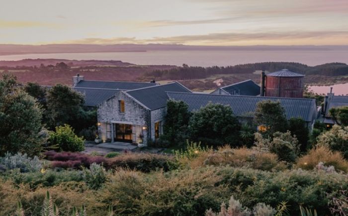 Scenic view of a resort surrounded by lush greenery and hills at sunset, showcasing the tranquil atmosphere of New Zealand's landscapes.