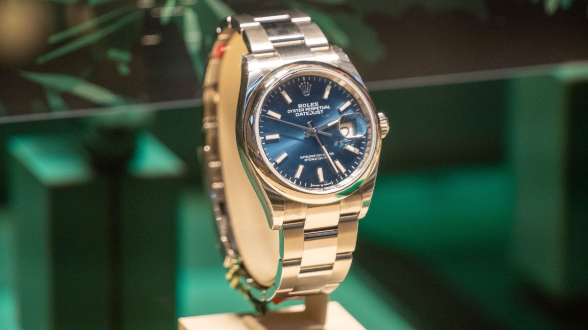 Rolex Oyster Perpetual Datejust watch displayed with a blue dial and stainless steel bracelet on a pedestal.