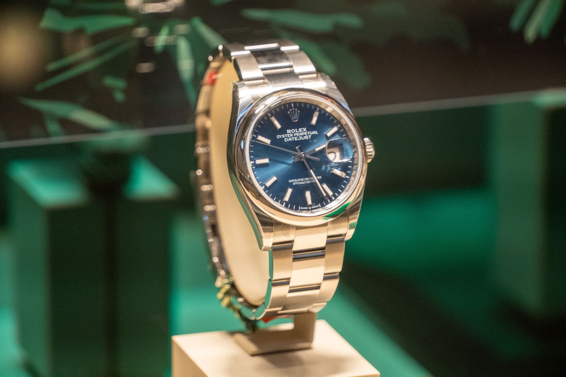Rolex Oyster Perpetual Datejust watch displayed with a blue dial and stainless steel bracelet on a pedestal.