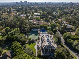 Aerial view of the Rosewood Estate showcasing lush gardens, a tennis court, swimming pool, and the Bel-Air skyline in the background.