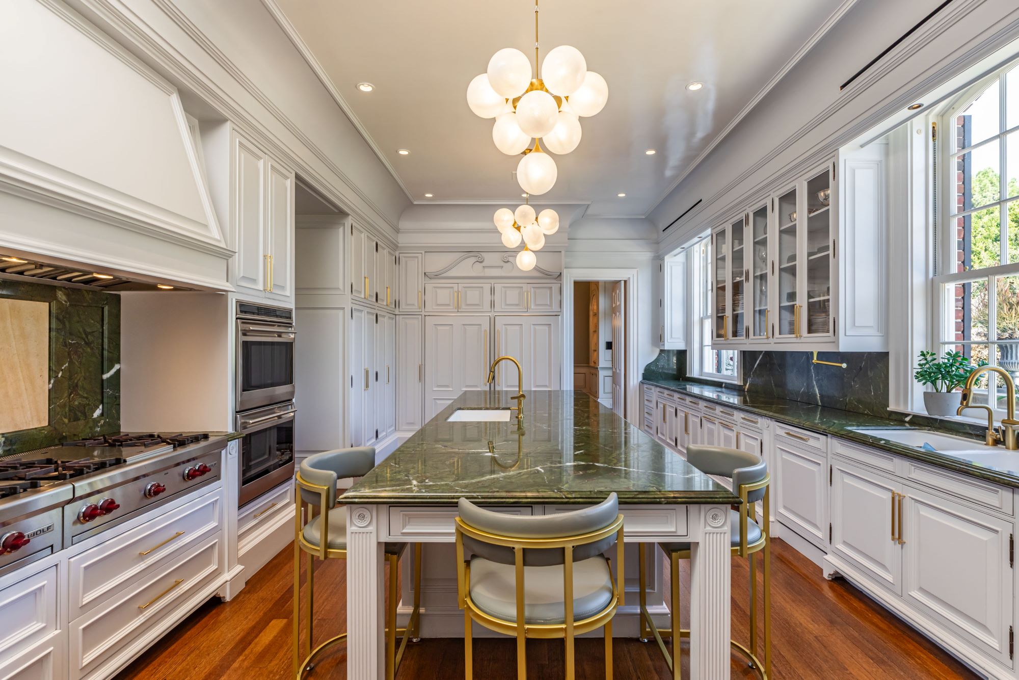 Luxurious kitchen featuring green marble countertops, high-end appliances, and modern lighting in a sophisticated design.