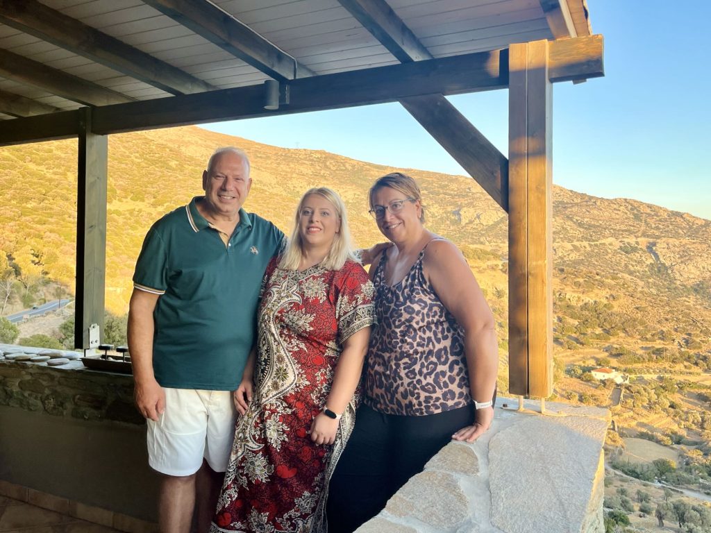 Guests enjoying a scenic view at Aegean Castle, a luxury boutique hotel on Andros Island, with friendly staff nearby.