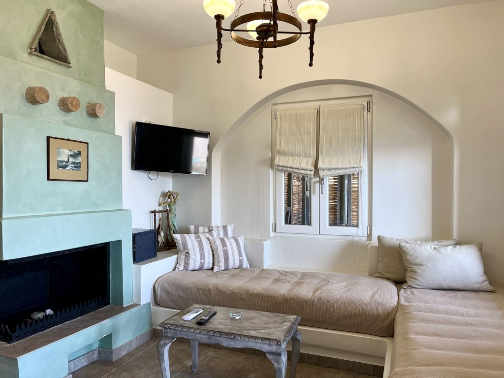 Stylish interior of a luxury boutique hotel room with cozy seating, a green fireplace, and natural light from the windows.