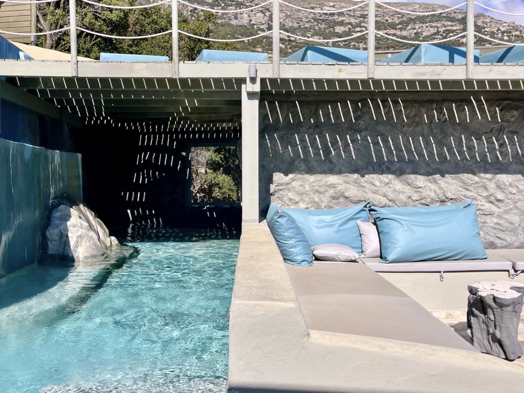Contemporary lounge area with turquoise cushions beside a serene swimming pool at Aegean Castle hotel on Andros Island.