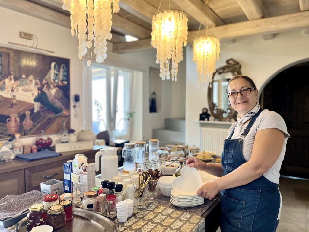 Staff member preparing plates in the dining area of Aegean Castle, a luxury boutique hotel on Andros Island.