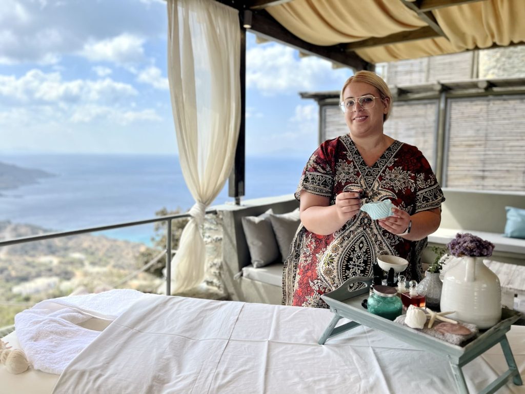 A staff member presents spa products on a terrace overlooking the sea at Aegean Castle on Andros Island.