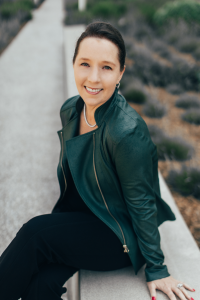 Marcia Dawood smiling in a green jacket, promoting her book "Unapologetic Wealth" aimed at empowering women and finances.