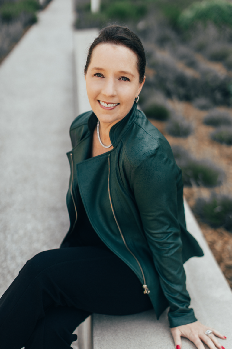 Marcia Dawood smiling in a green jacket, promoting her book "Unapologetic Wealth" aimed at empowering women and finances.
