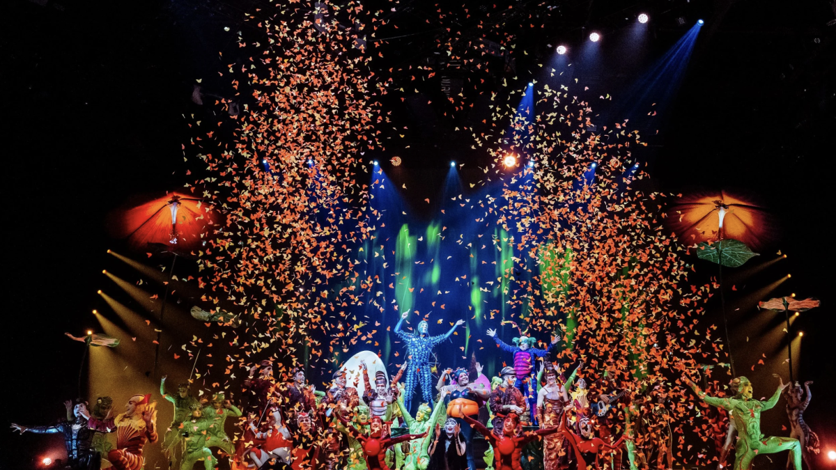 A colorful scene from Cirque du Soleil’s OVO performance with performers celebrating amid cascading confetti.