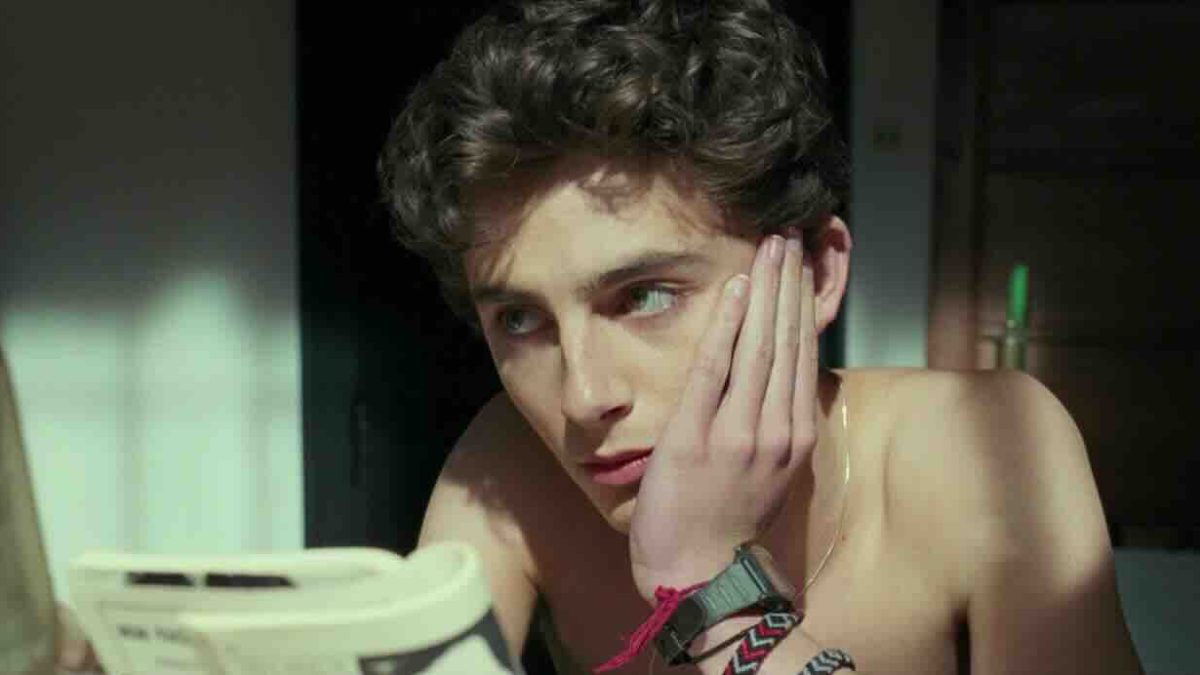 Timothée Chalamet resting his chin on his hand, appearing thoughtful while looking off-screen.