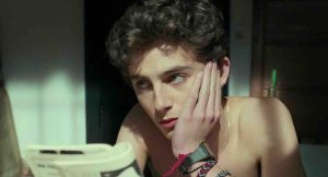 Timothée Chalamet resting his chin on his hand, appearing thoughtful while looking off-screen.