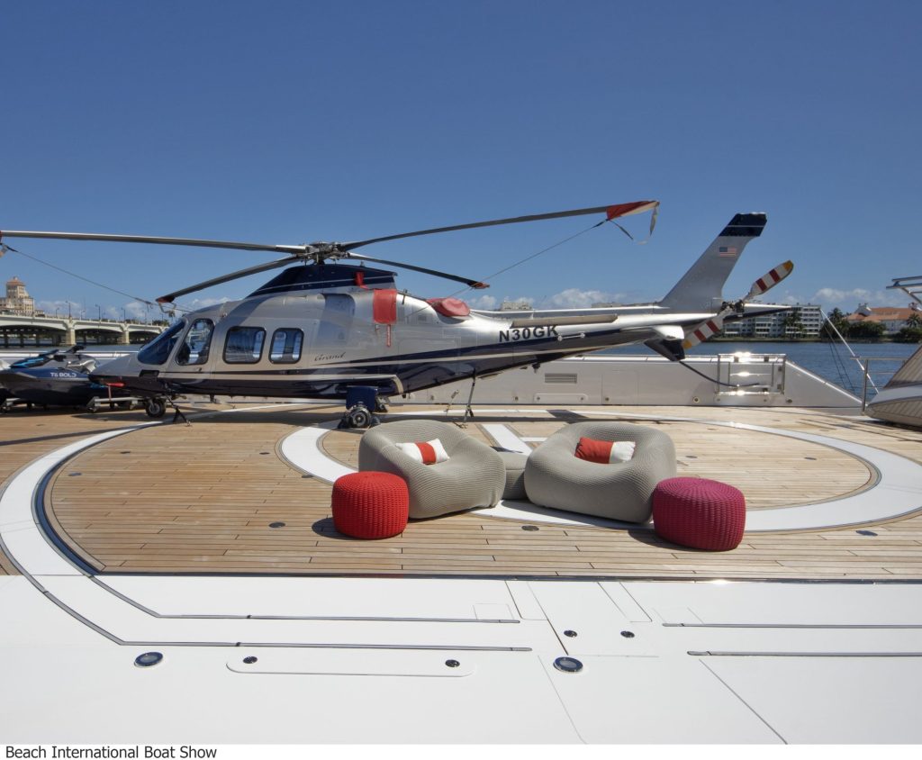 A sleek helicopter on a luxury yacht deck with modern seating near the Palm Beach International Boat Show.