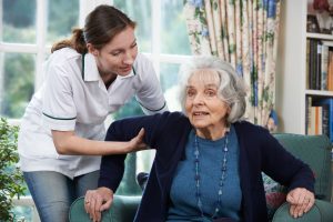 A caregiver assists an elderly woman in a cozy living room, illustrating the importance of support in understanding dementia.