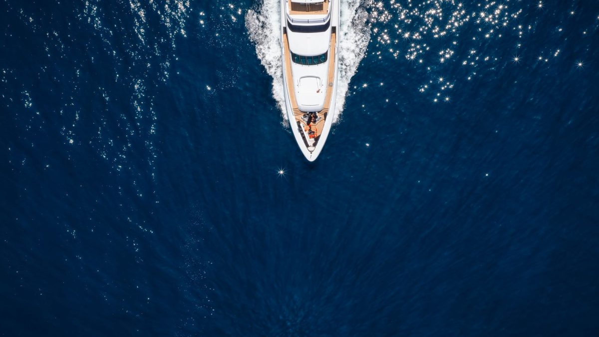 A luxury yacht cruising over sparkling blue waters, illustrating the exclusivity of the ultra-rich lifestyle.