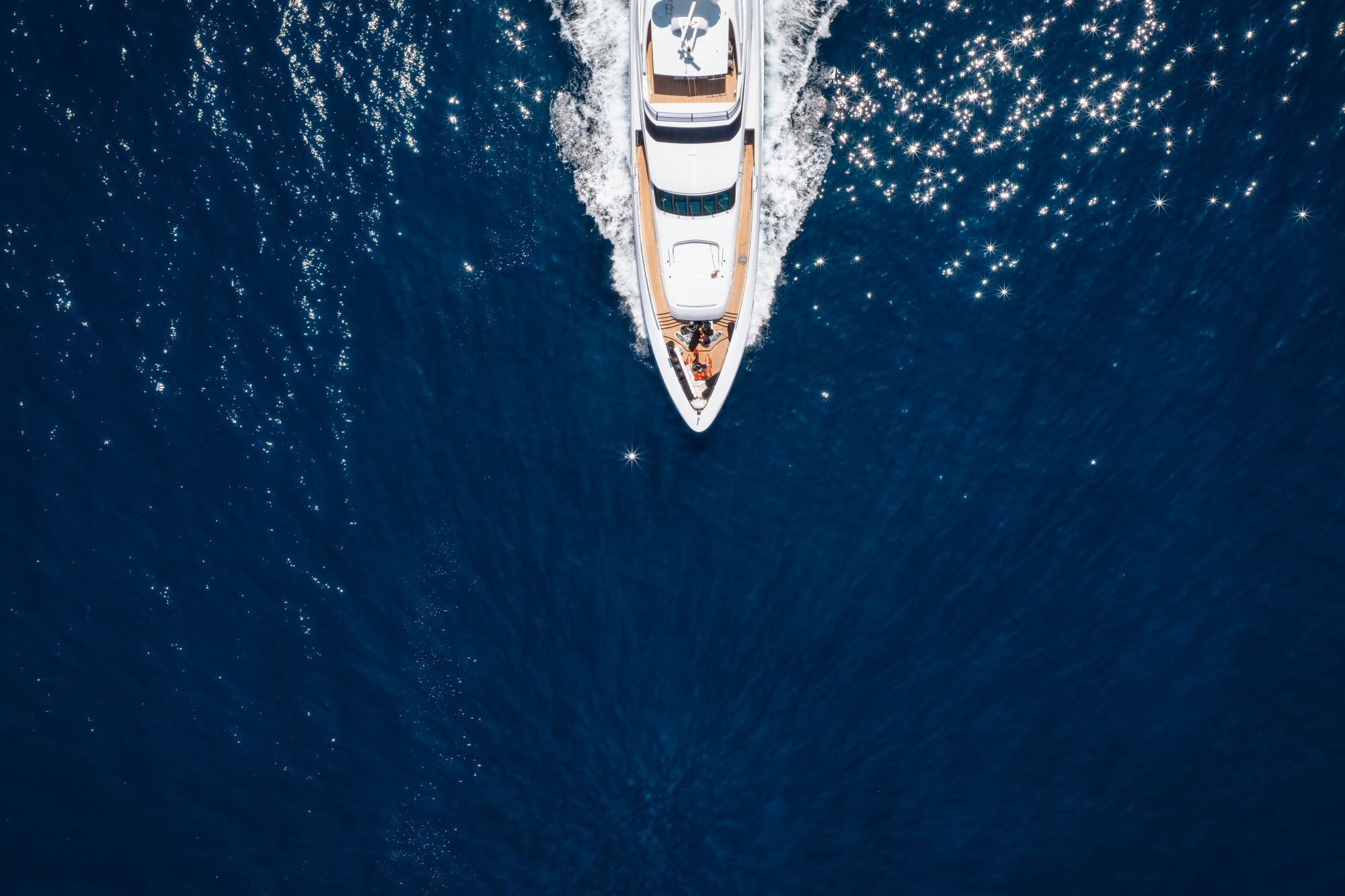 A luxury yacht cruising over sparkling blue waters, illustrating the exclusivity of the ultra-rich lifestyle.