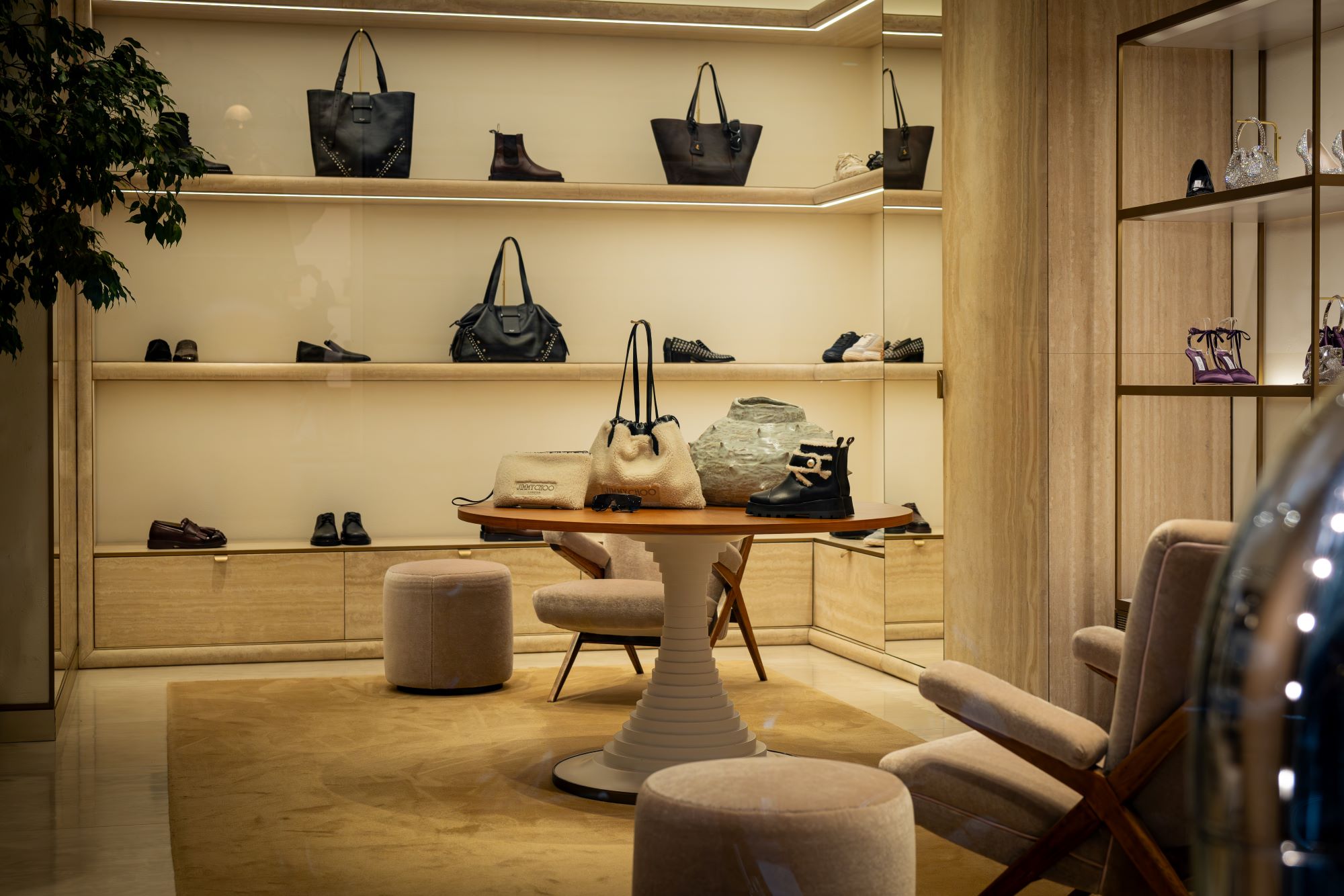 Luxury retail space featuring various designer handbags and shoes displayed on a minimalist shelving unit.