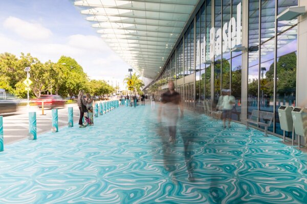 Visitors walking along a vibrant, marbled blue pathway at the entrance of Art Basel Miami Beach.