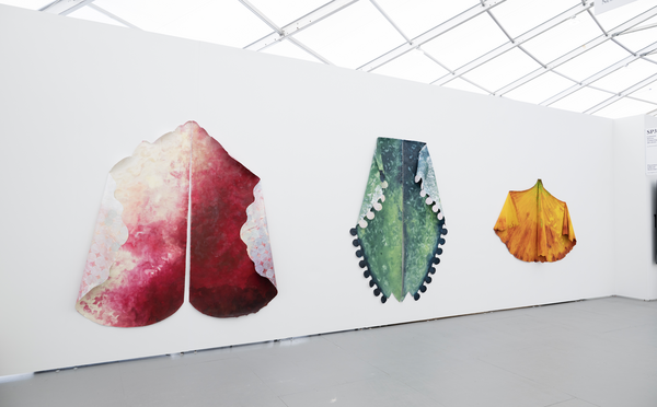 Three vibrant, abstract fabric artworks displayed on a white wall at Art Basel Miami Beach 2025.