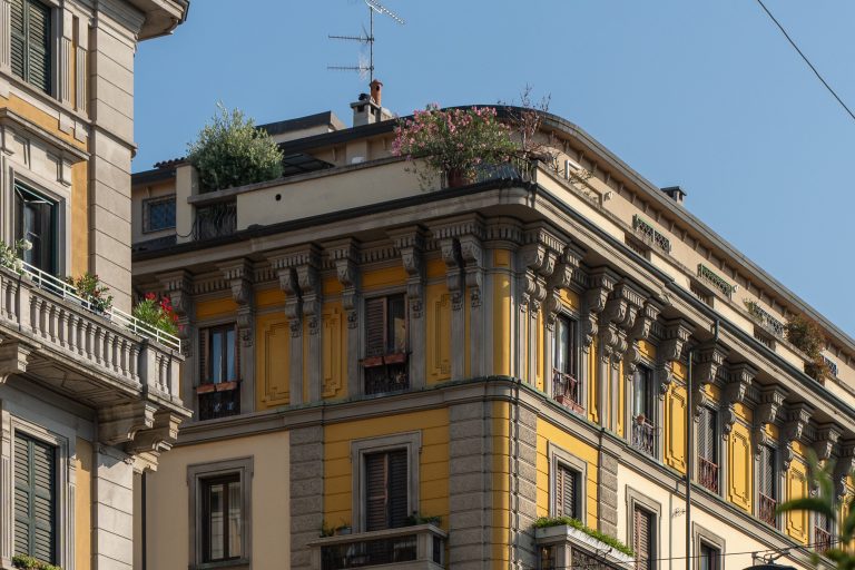 Historic building with ornate architecture and greenery on the rooftops, highlighting the design of Hotel Milu Milano.