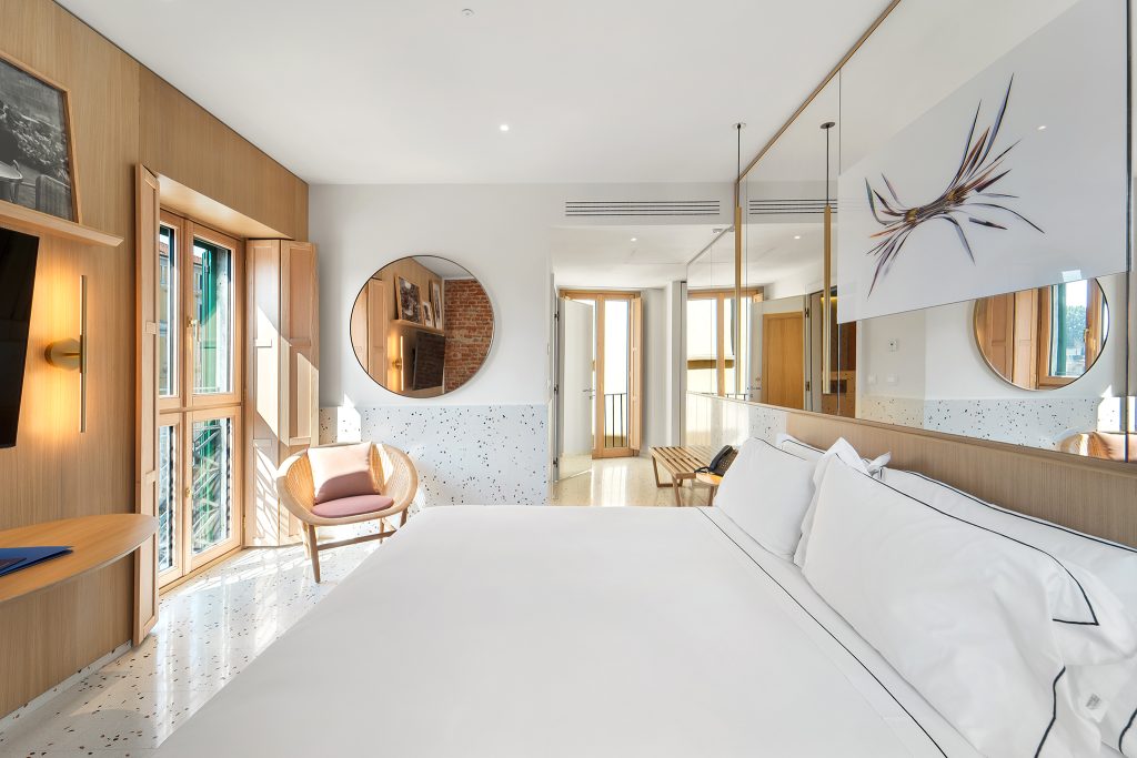 Stylish hotel room at Hotel Milu Milano featuring a bed, seating area, and large windows with natural light.