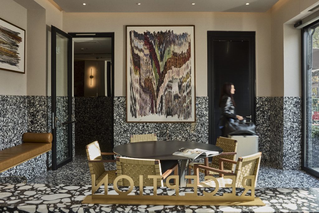 Elegant hotel reception area featuring unique artwork and modern furniture, with a guest approaching the entrance.