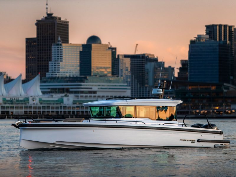 Axopar 37 XC boat cruising in front of a city skyline at sunset, showcasing modern design and luxury yachting.
