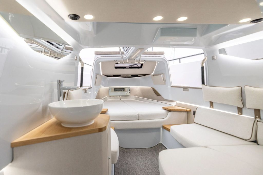 Modern yacht interior featuring a spacious seating area, kitchenette, and a comfortable sleeping space with natural light.