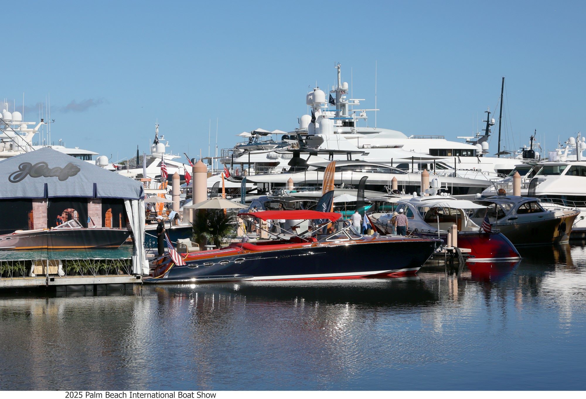 Boats docked at the Palm Beach International Boat Show, featuring yachts and a tent with dining options.