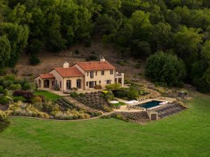 Luxury home with a terracotta roof, beautifully landscaped gardens, and a swimming pool set in a serene natural environment.