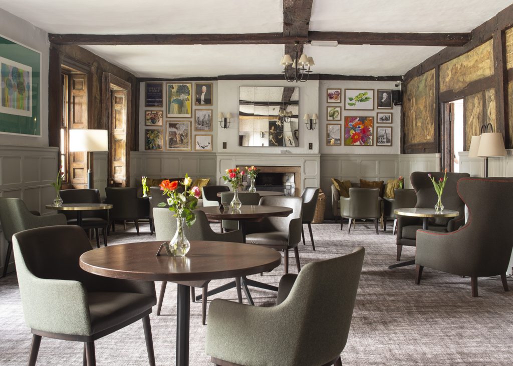 Stylish interior of The Bush Farnham featuring comfortable seating, floral arrangements, and artistic decor on the walls.