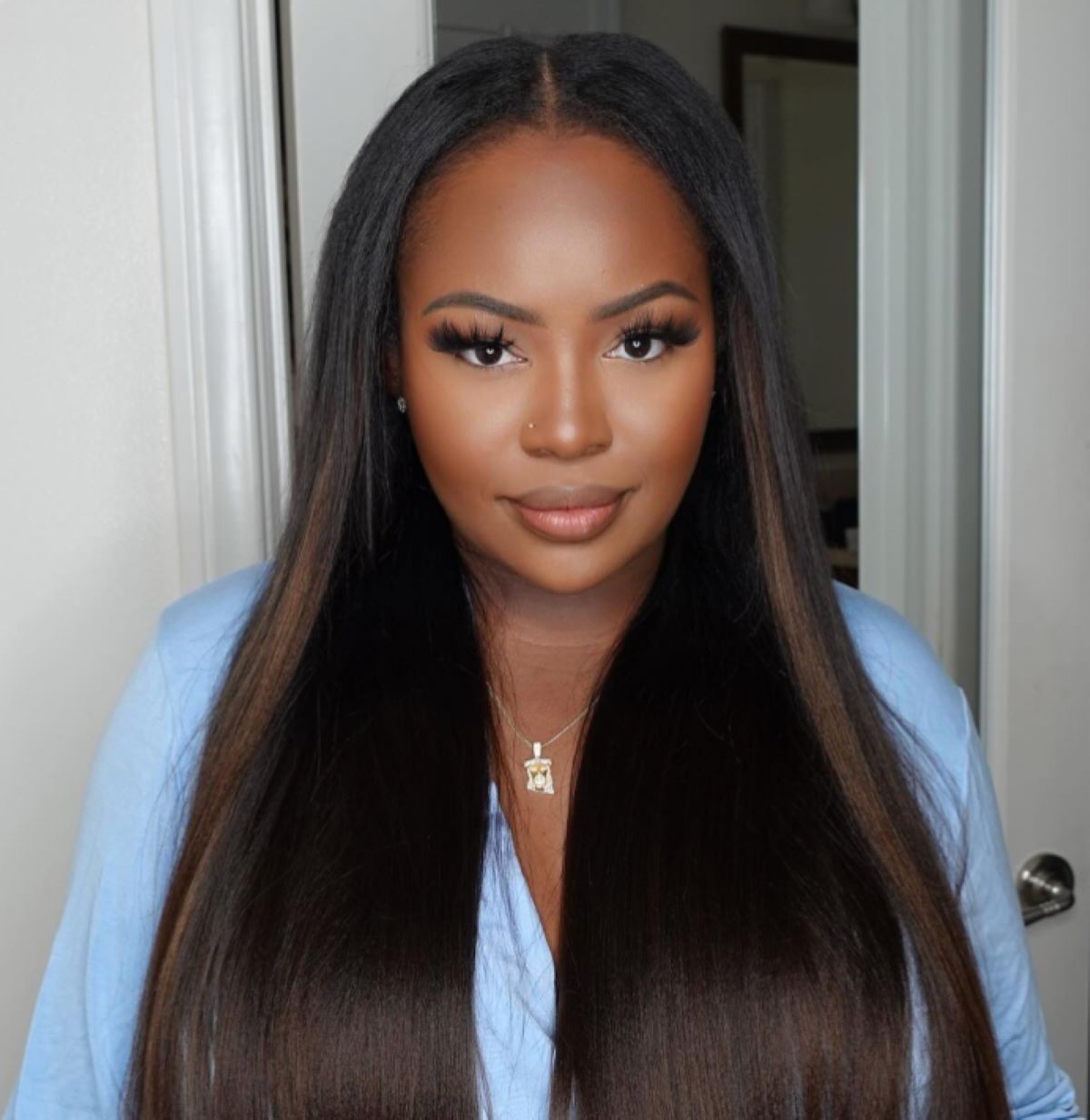 Woman with long, straight, dark hair styled in beautiful layers, wearing a blue top and subtle makeup, showcasing Nadula hair bundles.