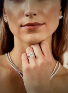 A close-up of a person wearing an engagement ring and elegant jewelry, showcasing trends in personalized engagement rings.