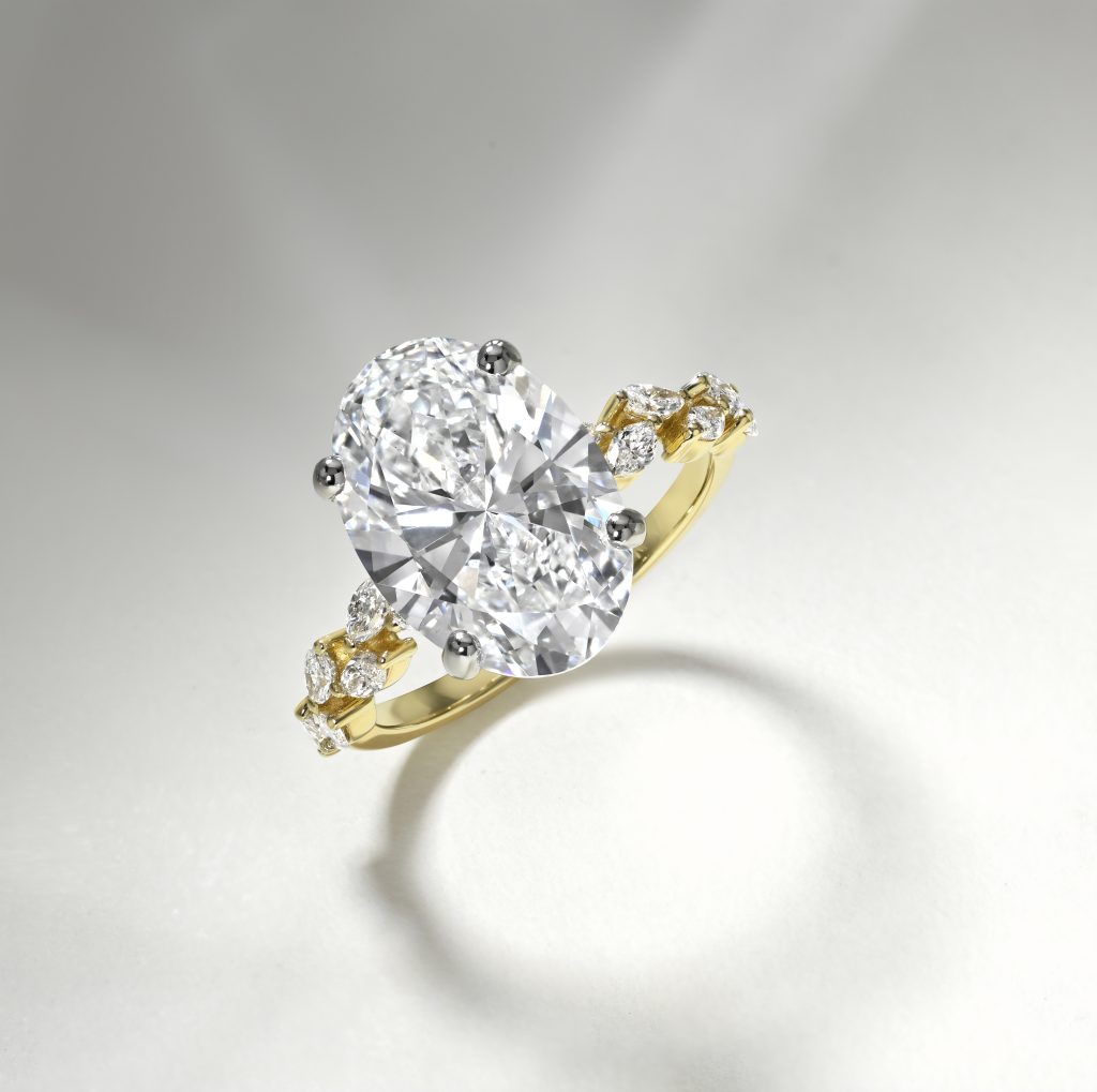 Oval diamond engagement ring set in yellow gold with smaller diamonds on the band, showcasing a blend of elegance and personalization.