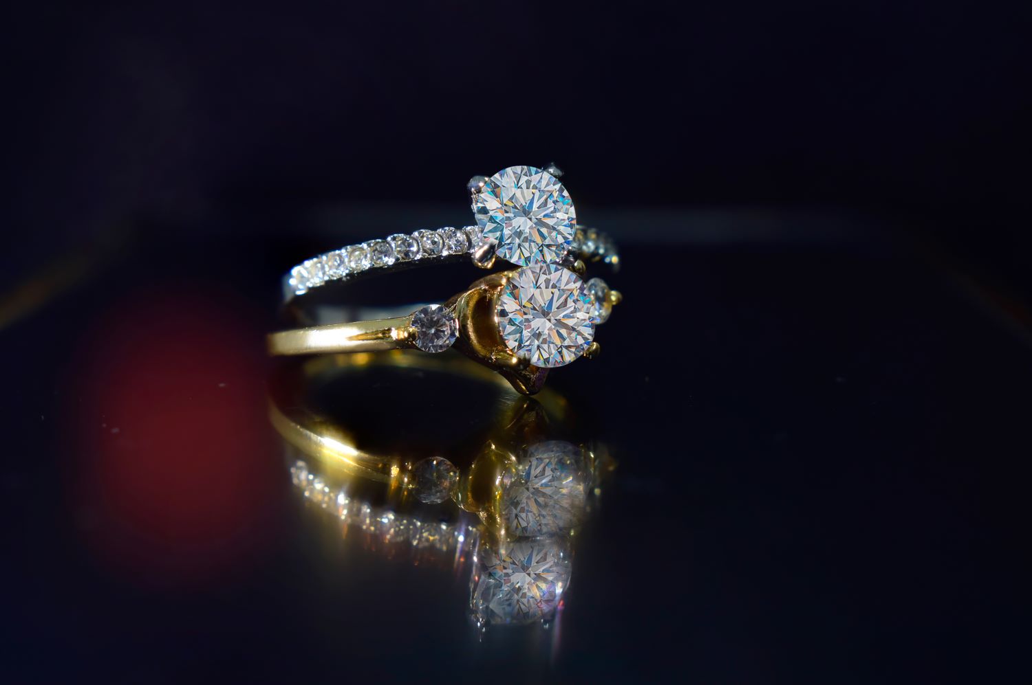 Elegant gold engagement ring featuring two prominent round diamonds and a sparkling band with smaller stones.