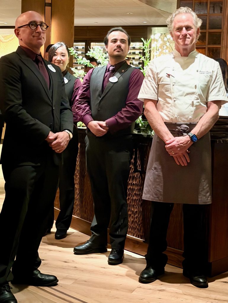 Four staff members in formal attire stand together in the upscale Napa Rose restaurant, with a focus on a chef in the center.