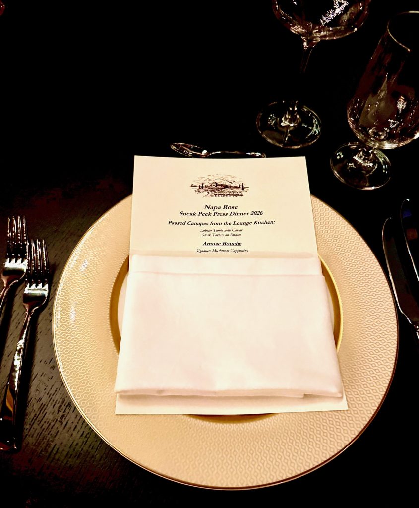Napa Rose press dinner menu displayed on an elegant plate, with fine cutlery and glassware in the background.